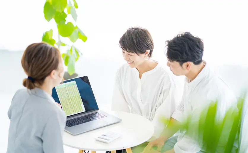 スーツ姿の女性から説明を受ける夫婦