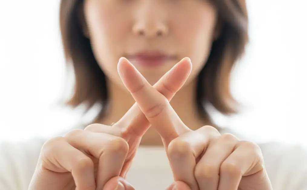 指をクロスする女性