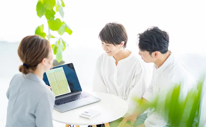 スーツ姿の女性から説明を受ける夫婦